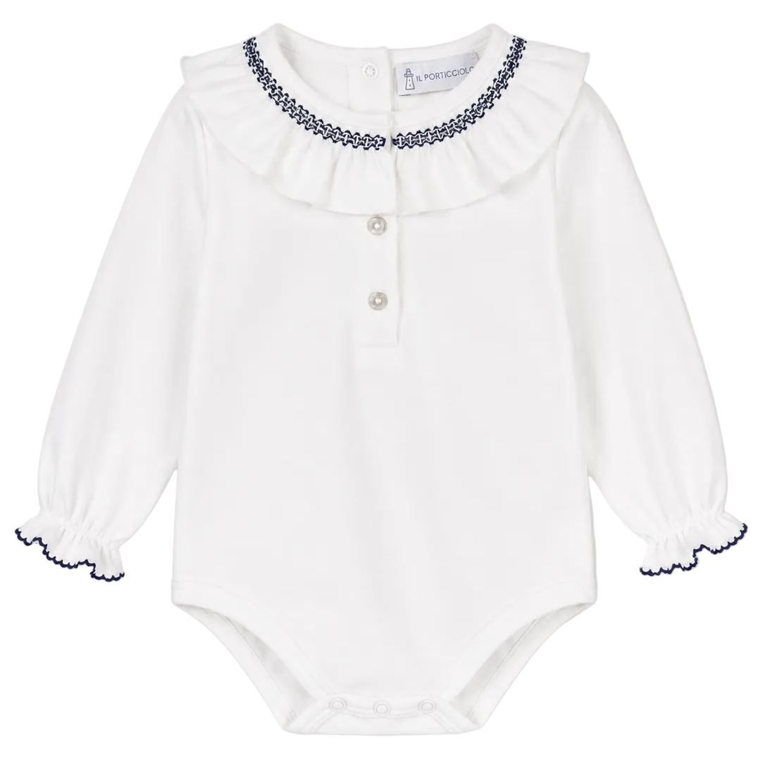 A white long-sleeve baby bodysuit with a ruffled collar, three-button placket, and navy blue embroidered trim details on the collar and cuffs.
